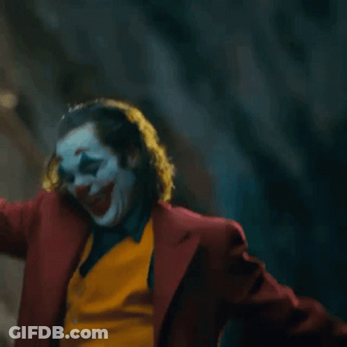 The Joker Is Standing On A Set Of Stairs With His Arms Outstretched . GIF