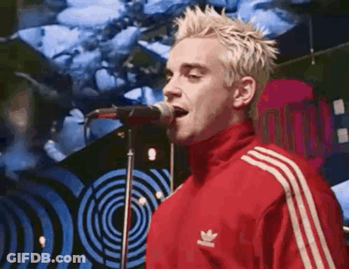 The Man Is Wearing A Red Adidas Jacket And Singing Into A Microphone . GIF