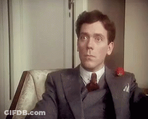The Man Is Wearing A Suit And Tie And Is Sitting In A Chair . GIF