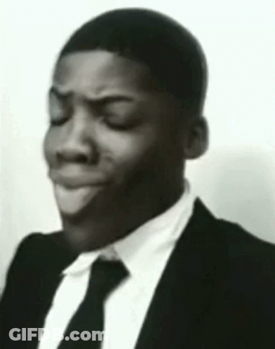 The Man Is Wearing A Suit And Tie And Making A Funny Face . GIF