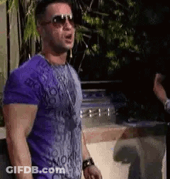 The Man Is Wearing Sunglasses And A Purple Shirt . GIF