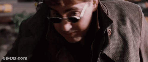 The Man Is Wearing Sunglasses And A Trench Coat . GIF