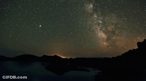 The Milky Way Is Visible In The Night Sky Over A Lake GIF