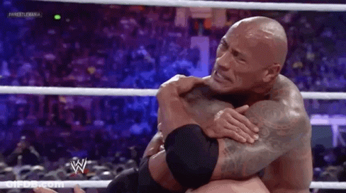 The Rock Is Hugging Another Wrestler In A Wrestling Ring . GIF