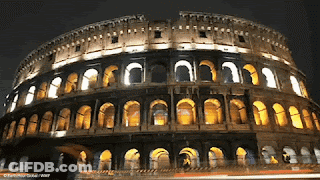 The Roman Colosseum Is Lit Up At Night And Has Arches And Windows GIF