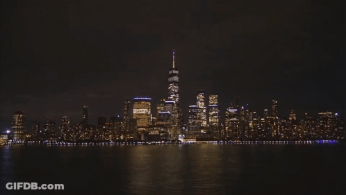 The Skyline Of New York City At Night With One World Trade Center In The Foreground GIF