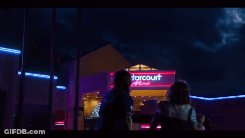 The Starcourt Mall Is Lit Up At Night With Neon Lights GIF