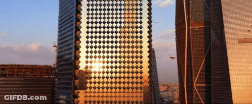 The Sun Is Reflected In A Building With A Checkered Pattern GIF