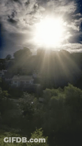 The Sun Is Shining Brightly Through The Clouds Over A Residential Area GIF
