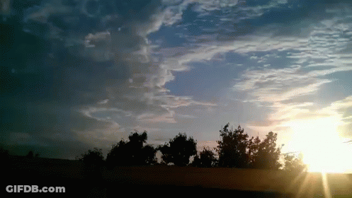 The Sun Is Shining Through The Clouds Over A Fence GIF
