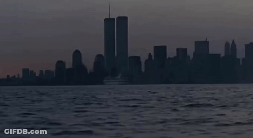 The Twin Towers Are Visible In The Distance Behind A Boat GIF