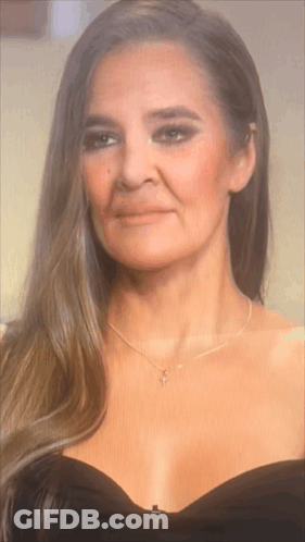 The Woman Is Wearing A Black Dress And A Necklace . GIF