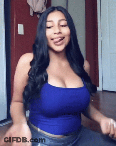The Woman Is Wearing A Blue Tank Top And Jeans And Has A Large Breast . GIF