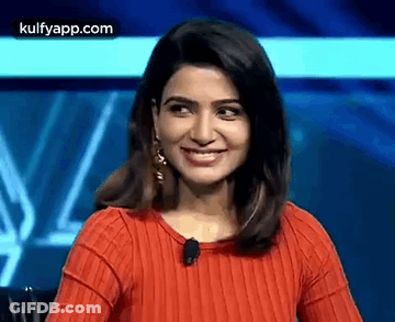The Woman Is Wearing A Red Sweater And Smiling . GIF
