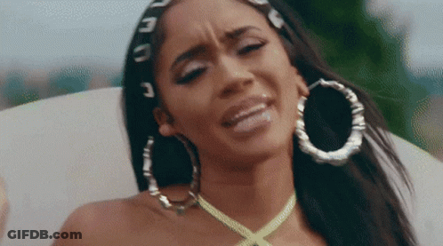 The Woman Is Wearing Hoop Earrings And A Yellow Necklace . GIF