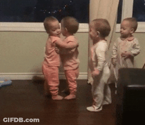 Three Babies In Pink Pajamas Are Hugging Each Other GIF