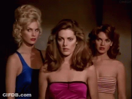 Three Beautiful Women Are Standing Next To Each Other In A Dark Room . GIF