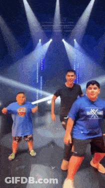 Three Boys Are Dancing On A Stage In Front Of A Stage With Lights . GIF