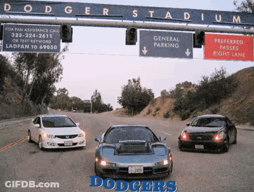 Three Cars Are Parked Under A Dodgers Stadium Sign GIF