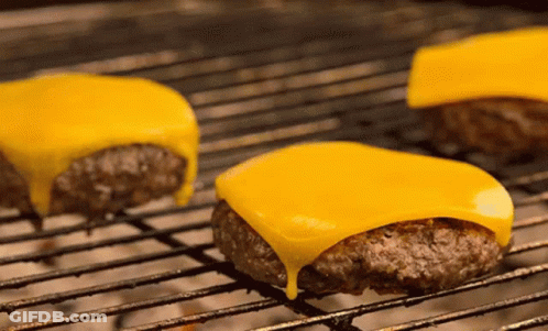 Three Cheeseburgers Cooking On Grill GIF