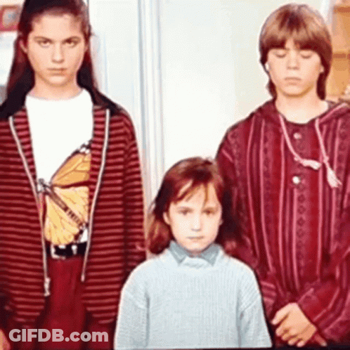 Three Children Are Standing Next To Each Other In A Room . One Of The Children Is Wearing A Butterfly Shirt . GIF