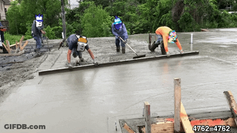 Three Construction Workers Are Working On A Concrete Floor GIF