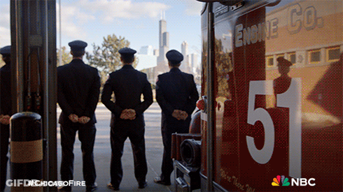 Three Firefighters Stand In Front Of A Chicago Fire Truck GIF