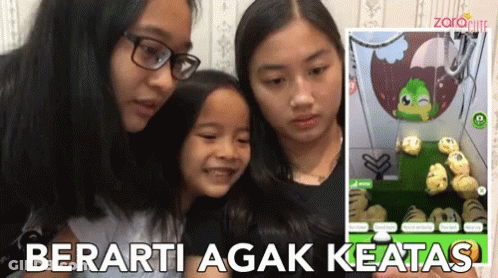 Three Girls Are Looking At A Screen With The Words Berarti Agak Keatas On The Bottom GIF
