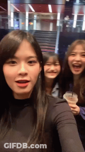 Three Girls Are Posing For A Picture And One Is Holding A Cup Of Coffee GIF