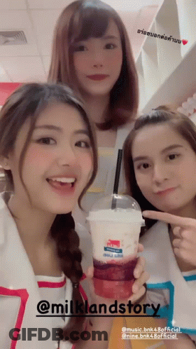 Three Girls Are Posing For A Picture With A Drink That Says Milklandstory On It GIF