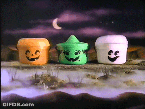 Three Halloween Buckets With Faces Painted On Them Are Sitting On A Rock GIF