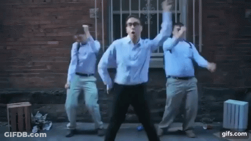 Three Men Are Dancing In Front Of A Brick Building . GIF