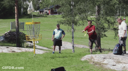 Three Men Are Playing Frisbee Golf In A Field With A Yellow Frisbee Basket GIF