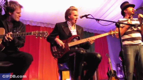 Three Men Are Playing Guitars And Singing Into Microphones GIF