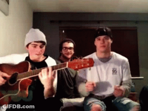 Three Men Are Playing Guitars In A Living Room . GIF