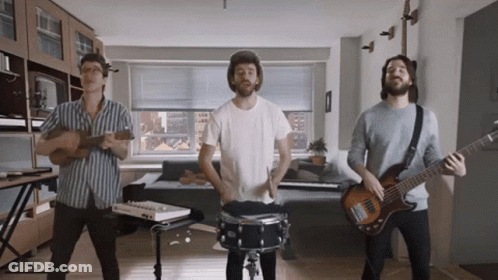 Three Men Are Playing Instruments In A Living Room And One Is Playing A Bass Guitar GIF