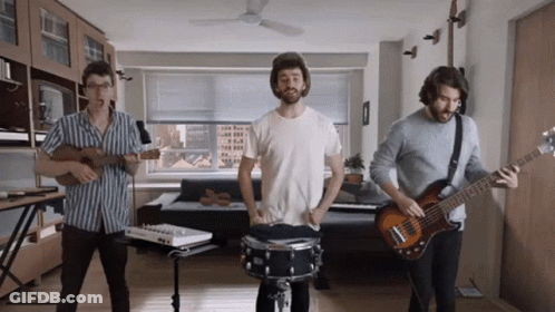 Three Men Are Playing Instruments In A Living Room Including A Drummer GIF