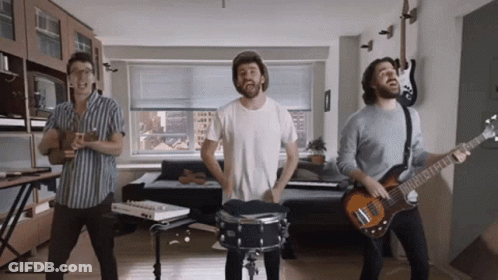 Three Men Are Playing Instruments In A Living Room Including A Drummer And A Guitar Player GIF