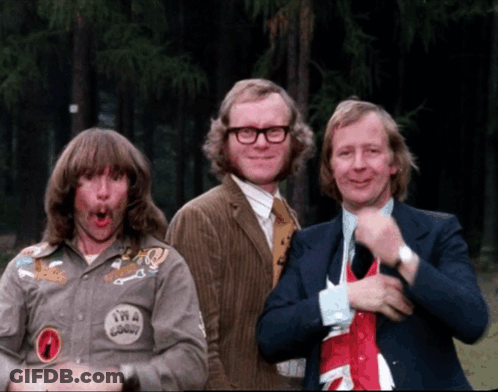 Three Men Are Posing For A Picture And One Of Them Has A Patch On His Shirt That Says Twa Goody GIF