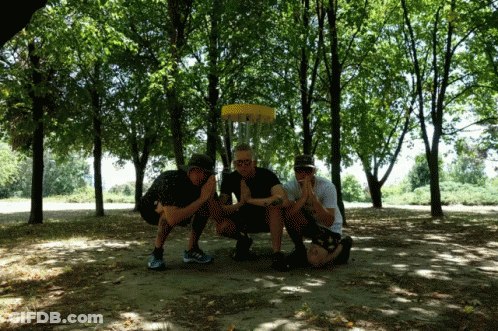 Three Men Are Posing For A Picture In Front Of A Frisbee GIF