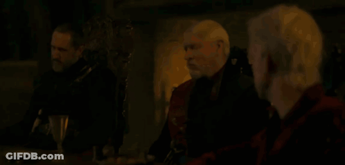 Three Men Are Sitting At A Table In A Dark Room Talking . GIF