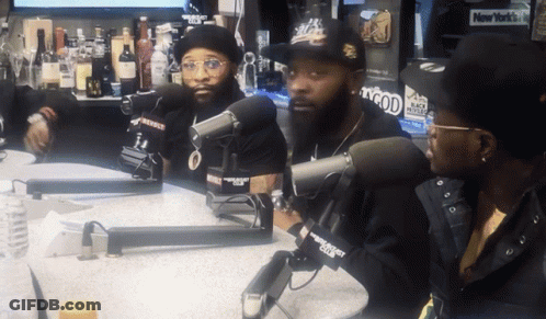 Three Men Are Sitting At A Table With Microphones In Front Of Them And A New York Times Sign In The Background GIF