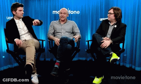 Three Men Are Sitting In Chairs In Front Of A Blue Curtain That Says Movietone GIF
