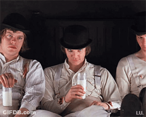 Three Men Are Sitting Next To Each Other And One Is Drinking Milk GIF