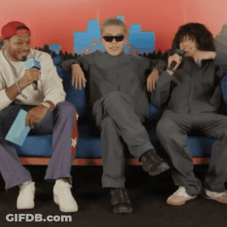 Three Men Are Sitting On A Couch And One Of Them Is Holding A Microphone GIF