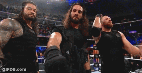 Three Men Are Standing In A Wrestling Ring Holding Hands . GIF