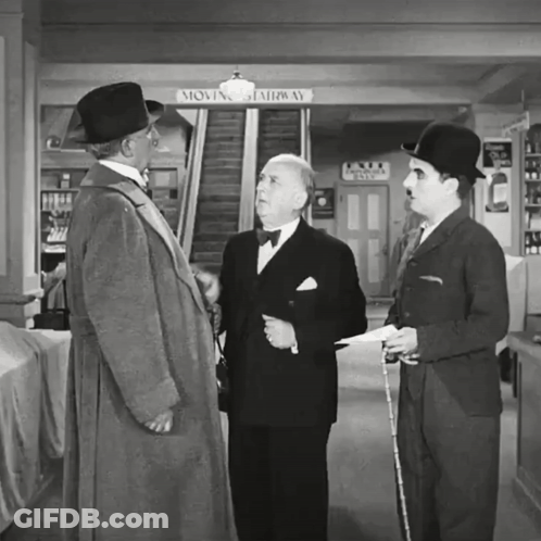 Three Men Are Standing In Front Of A Moving Stairway Sign GIF