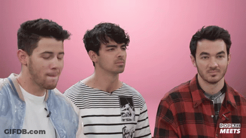 Three Men Are Standing In Front Of A Pink Background That Says Pop Blitz Meets On It GIF