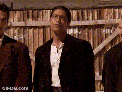 Three Men Are Standing In Front Of A Wooden Fence GIF