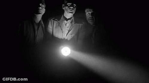 Three Men Are Standing In The Dark Holding A Light . GIF